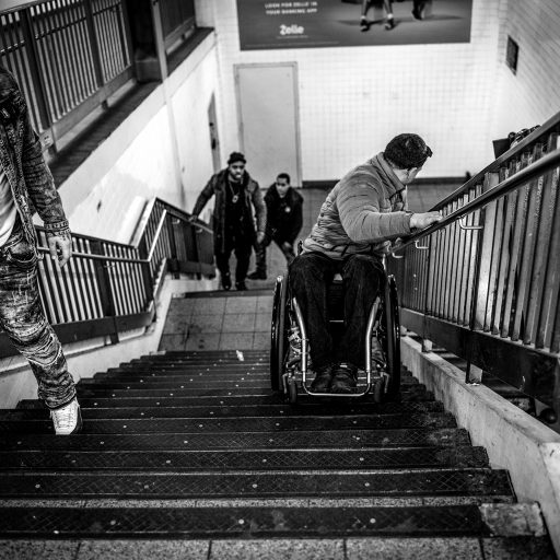 Nolan Ryan Trowe, VII Mentor Program, January 2018, New York, New York: Alex Haly rides down the stairs of the 14th St/ 8th Av. Subway station backwards in his wheelchair. The elevator is out of service.