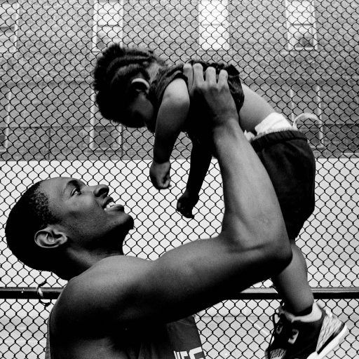 Nolan Ryan Trowe, VII Mentor Program, June 2018; West 4th Street Courts, Manhattan: A young man lifts a child over his head after a league game at the West 4th streetball courts.