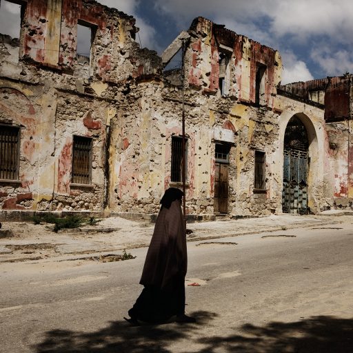 A woman walks along side the skeletal remnants of bullet-ridden buildings in the Shangani neighborhood of Mogadishu, Benadir region, Somalia on Nov. 13, 2008. Nearly two years after Ethiopian forces led an armed intervention to oust Somalia's Islamic Courts Union from power, the impoverished country has seen some of the deadliest violence in its history. A staggering 600,000 Somalis have fled the capital city from February to November of 2007 alone. Nearly half of the city is deserted with over one million internally displaced persons, IDPs, taking refuge in one of the hundreds of over crowded camps in and around the city.