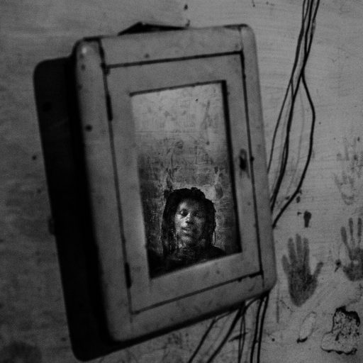 In May, 2015, a young woman stands on her room inside the IBGE building, a public building that is a part of the Favela da Mangueira. The mirror is one of the few furniture she owns and it stands along her children's hand print on the wall decorating their small home. Mangueira is one of the most famous favelas in Rio de Janeiro for its tradition in samba. It is located in Rio's north zone, a few steps away from Maracana, the biggest football stadium in the city, which received near two billion Reais on public investments for the 2014 World Cup. The misdirection on the government attention, makes the abandoned building, a social disaster as they don't have piped water, collection of garbage or any other public service.   The occupants, in most cases, are people who lost their jobs and with no more incomes, only donations or a little help from relatives, are not able to pay rent or get a decent place to live.