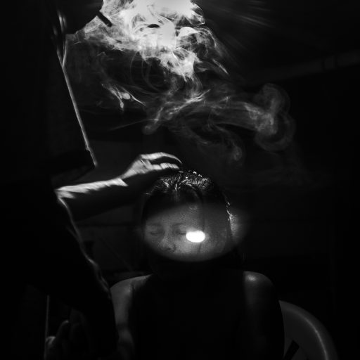 In May, 2017, Aladino, a native Bora shaman, blows smoke on his patient's head during one of the healing sessions late at night. The house is located in Pebas, a small village in the Peruvian Amazon. Before blowing the smoke, he performs a prayer in Bora language and asks the spirits to guide him throughout the process. The spiritual process is to make a woman called Marili, who feels sick from her stomach and is facing trouble sleeping, better again. Aladino says that the duty of a natural healer is to work with all kind of diseases from headaches, which can take a day, to the worse like malediction, which can take weeks.