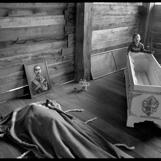 Chiang Mai, Thailand. Too young to know what is happening, a boy plays with his mother's coffin before her body is placed inside. She died of AIDS after contracting the disease from her husband who had frequented brothels.