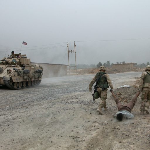 U.S. troops from Charlie Company remove a dead body from the road, northern outskirts of Baghdad, April 2003.