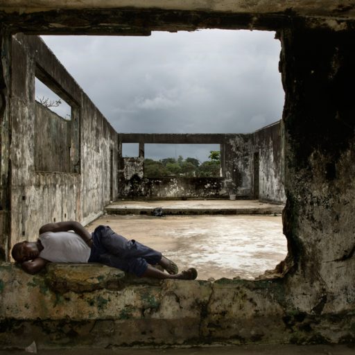 A former child soldier rests on the wall of a damaged building in the Tortoise community of Monrovia, Liberia on Sept. 14, 2008.