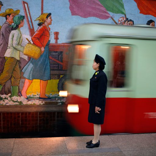 Behind the Curtains series — An attendant stands near the tracks as a metro train arrives in the station in the subway of Pyongyang, North Korea.