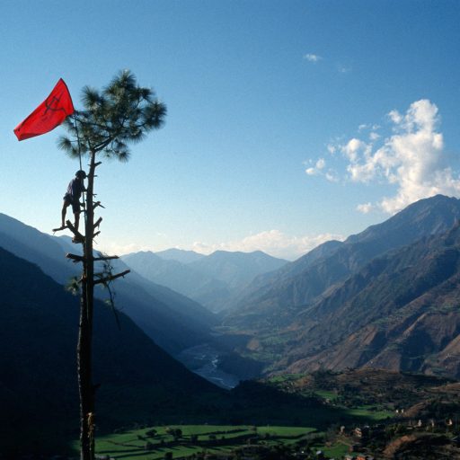 Behind the Curtains series — Nabin Pun, a Maoist rebel soldier of the People's Liberation Army, raises the communist flag from a tree above the village of Rukumkot, Nepal.