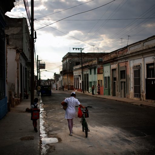 Behind the Curtains series — A nurse pushes her son's bicycle as he walks along side in Cienfuegos, Cuba.
