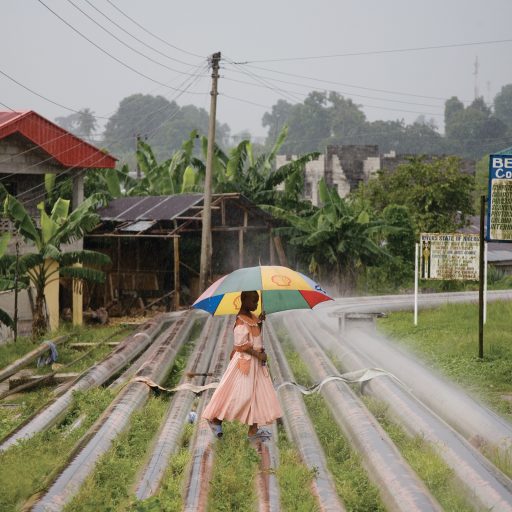 A young woman crossing oil pipelines that run through her community in Okrika, near Port Harcourt, Nigeria in the oil rich Niger Delta. 2006
