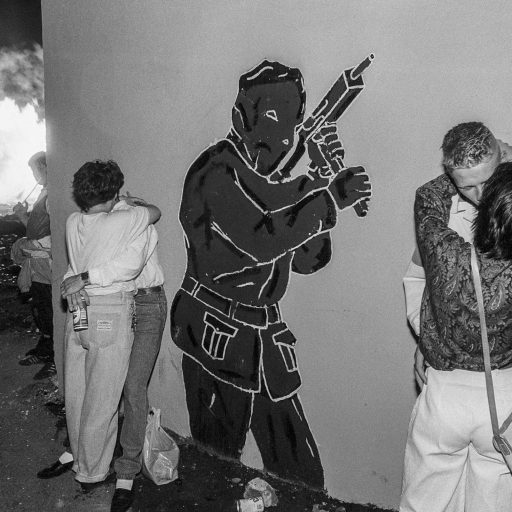 Teenagers from Belfast's working class Protestant neighborhood of Tiger's Bay, celebrate the 11th Night Bonfire under the ever-present symbol of the paramilitaries in Belfast, Northern Ireland on July 11, 1989.