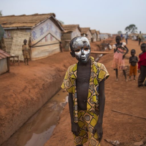 WAU, SOUTH SUDAN - MARCH 2017: John Francis (12), poses with a mask in the IDP camp in Wau, Western Bahr-el-Gazal, South Sudan. He found the mask and when he is  wearing the mask he entertains the children around him, who like to look at him and follow him around in the IDP camp. 
In 2017 the nation of South Sudan is only 6 years old. War broke out in December 2012 with widespread ethnic violence as a result of ongoing tensions over unresolved issues like the struggle for resources among the Sudanese people (access to land, cattle raiding and distribution of oil resources). Peace has been signed twice in the past years, this was a breakthrough to the people of South Sudan as there was high hope for peace after more than 2 years of conflict. But the people  were up for more shocks such as the fighting in Wau (June 2016) with more than 12.000 people displaced and more than 50 people were killed. Now the political conflict, compounded by economic woes and drought, has caused massive displacement, raging violence and dire food shortages. Over 5.1 million people are in need of aid, and 4.8 million are facing hunger. Due to economic collapse and three years of poor agricultural conditions, areas of South Sudan are now experiencing famine.