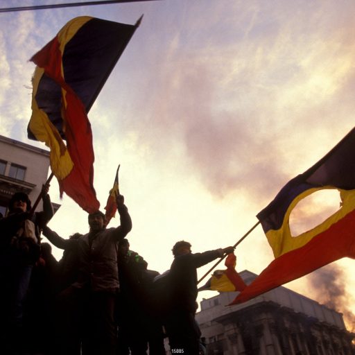 Jubilant civilians celebrate in the city's central square, waving national flags with the Communist coat of arms cut out of the centre. The Romanian popular revolt and coup of 22nd-25th December 1989 represented a decisive moment in the collapse of communism in Eastern Europe. An uprising which had begun a week earlier in the town of Timisoara spread to the capital city, Bucharest, with demonstrations leading to violent clashes in the streets. Nicolae Ceaucescu, President since 1974, lost the support of the army, who sided with ordinary civilians in street battles against the feared Securitate secret police force. As Ceaucescu and his wife Elena attempted to flee the country, they were captured, tried and executed. Their dead bodies were exhibited on television on Christmas Day. In just a few dramatic days, the country had rejected the communist system which had ruled since the Second World War. The slow and difficult transition to capitalism began.