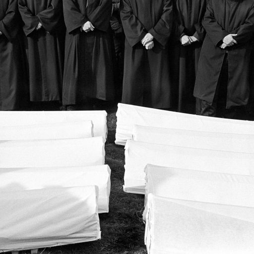 A line of imams pray as the bodies of forty Muslims  are prepared for reburial after being exhumed. The village of Visoko was ethnically cleansed in 1992, and most of the menfolk were shot on their doorsteps by Serbs from the next village. 18 people were killed here.