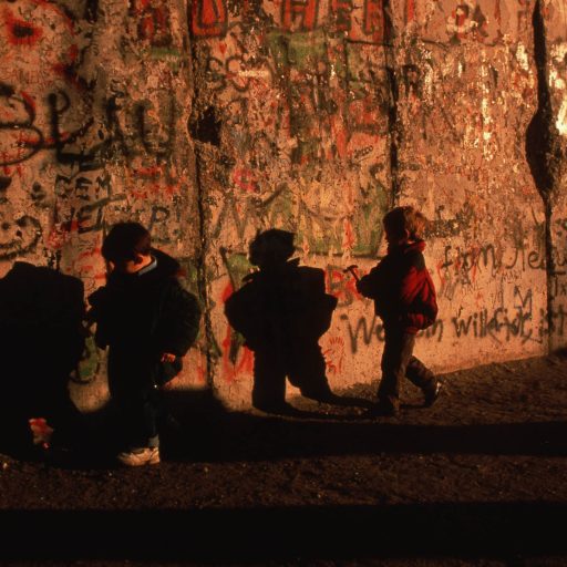 German children run alongside the Berlin wall as the wall came down and reunified East and West Germany.