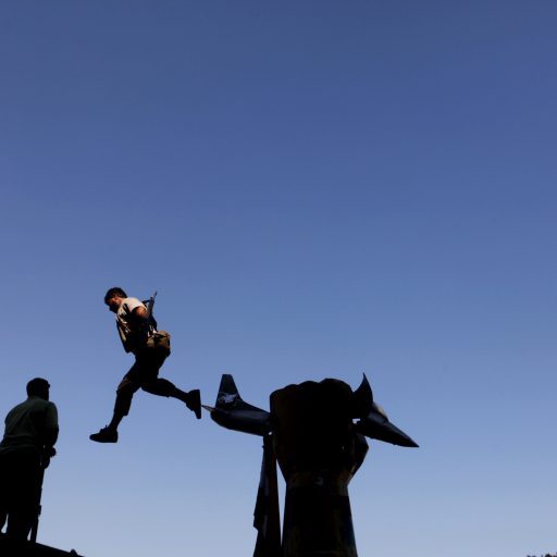 A rebel soldier jumps off Colonel Qaddafi's famous statue after the fall of his former Bab al-Aziziya compound during the Arab Spring in Libya.