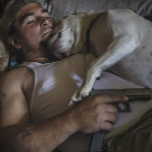 Militia leader Danny Bollinger (43) resting on a couch in his home in Maryland, USA,together with his pitbull and a pistol.
Danny says he is not religious but has a 'personal relationship with Jesus Christ', organised religion being what people kill each other over. Bollinger is the head of the militia 'My Brother's Threepers'. Bollinger and members of the group were present during the infamous 'unite the right' rally in Charlottesville in August 2017 but he insists they were there to hold the line between the Nazis and the anti-fascists, keeping them from killing each other.