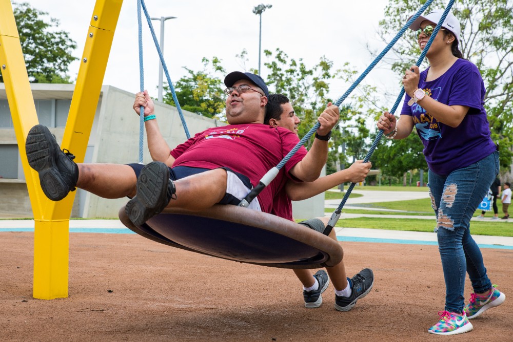  A MAVI employee pushes clients on a swing during a camp field trip to Parque Luis Muñoz Marín. 