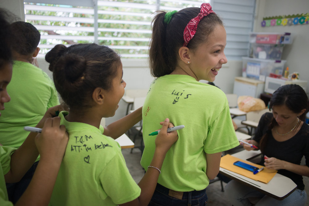  6/6/18 – Bayamón, Puerto Rico – The Puerto Rican Department of Education is closing 283 schools, and moving multiple schools into the same building, citing the past year’s drastic drop in enrollment as one of the primary reasons to lower the amount of schools, and instead increase the amount of students in each school. Students of special education schools are one of the groups to be most negatively affected by these closings, as the new schools may not offer the resources the students need and have access to at their current schools. La Escuela Aurelio Perez Martinez in the town of Bayamón is among the schools that will be closed. Sfudents in 4th and 5th grade sign each others' shirts on the last day of the school year. (Sofie Hecht Photography) 