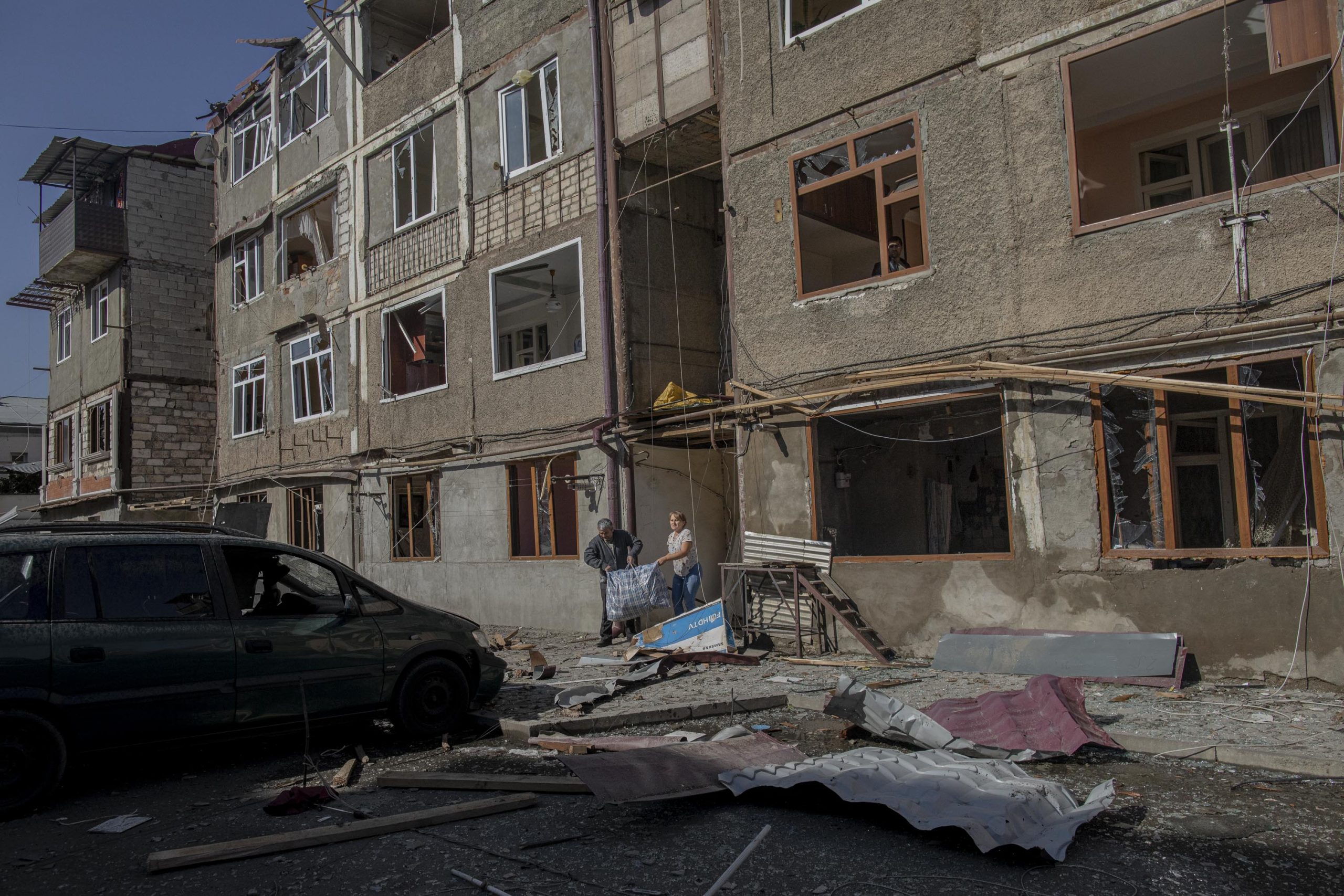 People carry their belongings out of a building damaged by a missile attack, in Stepanakert, Nagorno-Karabakh, on October 3, 2020. The building was damaged on the previous day, October 2.