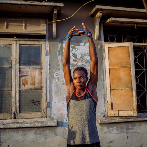 A female boxer stretches at a makeshift boxing space in Lagos.