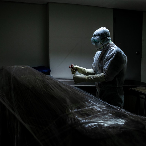 Mortuary staff sprays a plastic-wrapped coffin with a disinfectant, April 18, 2020. The corpse and the coffin must be wrapped with plastic wrappers and disinfected in every stage in order to suppress the spread of the virus.
