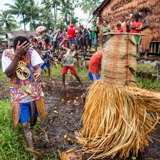 Villagers in Kapi tosses ‘red fruit’ (buah sanap) towards the manimar named 'Hamtar' from the Amnes clan during the Jipae resurrection feast, July 22, 2015. As manimar arrives in the village, the children will then playfully throw the manimar the fruits. The wearer is protected in the mask-basket.

The manimar in a jipae feast represents an orphan boy. According to legend, the orphan boy starts from stealing food from the village, and develops his cunning skills. As he wears the mask, he scares women out so that the women drop the food they gather in the forest. This trick is then revealed by the men of the village, who then agreed with the manimar to keep his secret to the trick and that orphans should not be left alone.