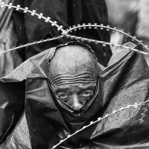 22.08.2015. Gevgelija, Macedonia (North Macedonia today). A refugee from Syria stares through barbed wire during a heavy downpour on no man's land between Greece and Macedonia. Thousands of refugees have been trapped for days and weeks in the open, exposed to extreme weather conditions, while waiting for a chance to continue their journey to Western Europe.
