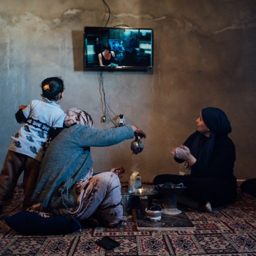 Hafsa al-Ansari drinks tea with her cousin, Aisha al-Ansari  while watching a movie on January 15, 2019 in Ubari, Libya.