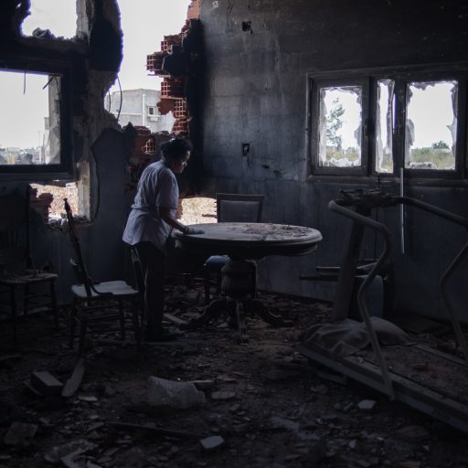 Lilia Delgado-Ramadan looks over items left in her destroyed dining room in her damaged house in Ain Zara, southern Tripoli on July 7, 2020 in Tripoli, Libya. (Photo by Nada Harib/Getty Images)