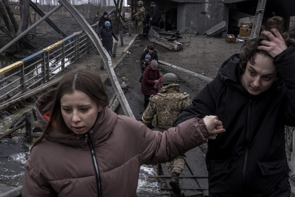 Photo by Ron Haviv / VII. People cross the Irpin river on the outskirts of Kyiv, Ukraine, Saturday, March 5, 2022, as they flee to safety after Russians supposedly bombed the rail tracks.  People were expecting to leave by train and couldn't in the end and fled by foot to eventual safety before some boarded buses to their next destination.