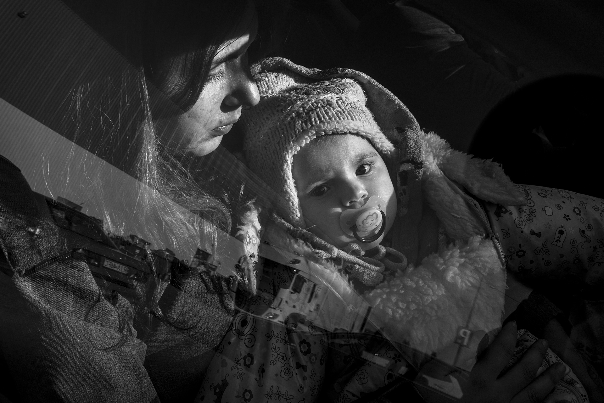 Photo by Joachim Ladefoged / VII. A refugee center in Hala Kijowska, Poland, on March 17, 2022. 24-year-old Angelika from Okhtyrka in eastern Ukraine holds her 10-month-old daughter Darina. They are getting a ride in the car of Polish volunteer Sandra, an insurance broker from Krakow, who has been driving to the border as often as she can to help transport refugees.