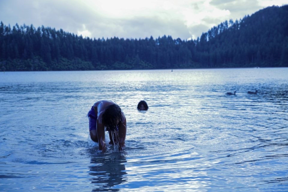 Tauamiti boys, swimming in Lake Tikitapu (Blue Lake). A family working holiday. They are of Samoan, Tongan, NZ European, Maori ancestry. Rotorua, Aotearoa NZ, January, 2022. By Emily Mafile’o