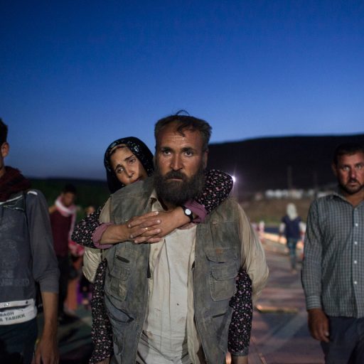 Aamir carries his wife Ghazala on his shoulder due to her weakened state from hunger and dehydration as they cross into Kurdistan, by way of the Syrian border in Faysh Khabur, Zakho, Iraq on Aug. 9, 2014.