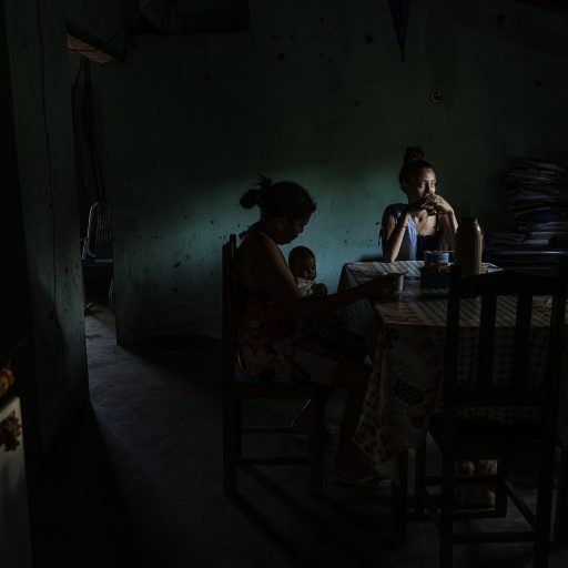 Chapada da Sindá, Piaui, Brazil, 8 de Agosto 2023. Marinalda Rodriguez da Silva, 42 (left) holds her grandson João Gabriel, 2 months old, while eating breakfast  with her daughter, Dailandia Silva Oliveira, 17. Marinalda is part of the quebradeira’s movement and whose main activity is working with the coconut, but Dailandia is studying  zootechnics. Her husband (Dailandia’s), like many young men in the region, is away working. © Adriana Zehbrauskas.