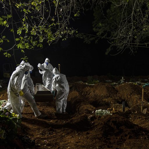 São Paulo, Brazil, April 13th, 2021. Employees of the  Vila Formosa Cemetery in Sao Paulo, Brazil, carry the coffin of a Covid-19 victim to be buried. Burials happen non stop throughout the day and into the evenings from 6 to 10 pm everyday. © Adriana Zehbrauskas.