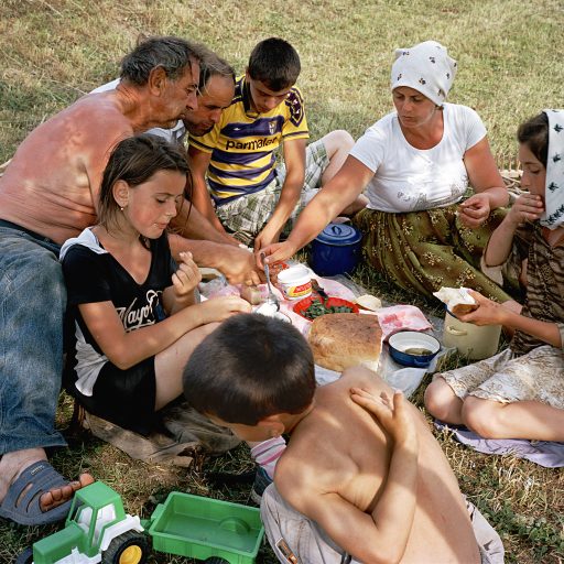 The Borca family relaxes after a working day that started early. Gheorghe (white shirt) and Anuța Borca (also in white) were married in July 1995, bang in the middle of the grass-cutting season. The honeymoon had to be shortened. “We started making hay again one week after the wedding,” Anuța says ruefully. This photograph was made in Maramureș, the Romanian-speaking part of northern Transylvania. Romania. June, 2012. © Rena Effendi.