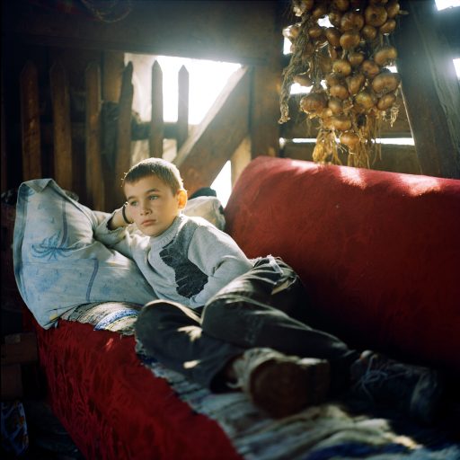 Andrei Rus, 12, relaxes in his father’s palinca still in Strâmtura. Palinca—the name for all kinds of fruit brandy—can be as much as 58 proof here. The stills require copious amounts of cooling water and are nearly always on the banks of streams—as are fulling machines, which use water-driven hammers to thicken up the fibers of woolen cloth. Maramures, Romania. November, 2012. © Rena Effendi.