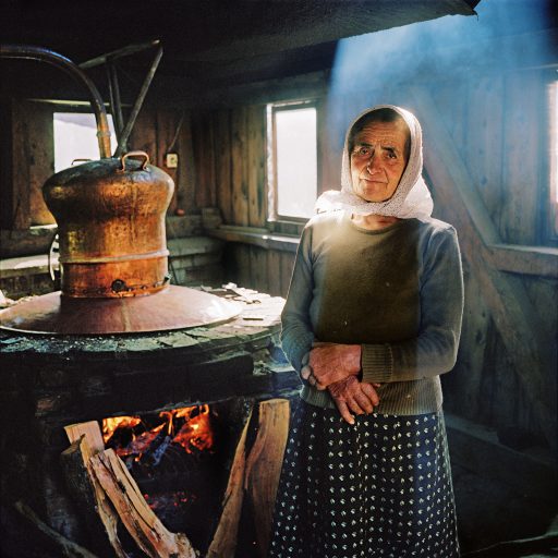 Anuța Vişovan, 70, tends the fire at a still owned by her neighbor, in Breb, for making palinca, the plum, apple, or pear brandy whose name means simply “distilled spirit.” A fiercely delicious dram of it is given to every visitor. “When the first thing you do is have some palinca,” Lorinț Opriş, mill owner at Sârbi, says, “you know it’s going to be a good day.” Maramures, Romania. October, 2012. © Rena Effendi.