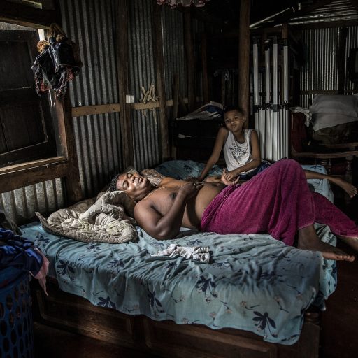 Pascale Rasafindakoto, 44, a “commissionaire,” or street trader, lies at home in bed near two of his sons, in Sambava in Madagascar's northeastern Sava region. © Finbarr O’Reilly.