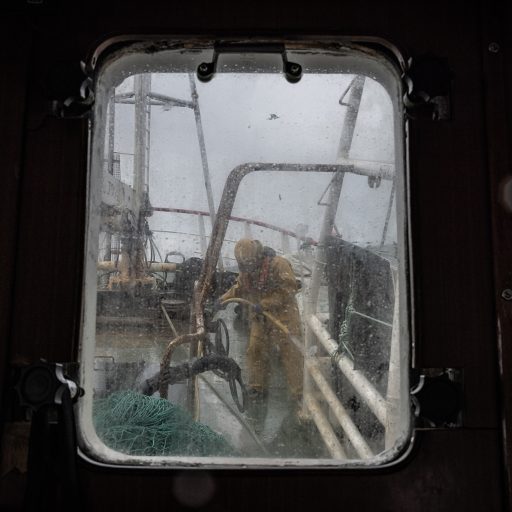 A crew member hoses down the deck aboard the fishing vessel Aquila on the ship’s final voyage, April 4, 2023. The Aquila is being scrapped as part of Ireland’s controversial government decommissioning scheme to reduce by about 30% the number of Irish fishing boats operating in local waters.  Already hammered by overfishing, the increased price of fuel and energy, inflation, geopolitics, and climate change—the Irish fishing industry is now at risk of collapse due to changes in trade rules triggered by Brexit—potentially wiping out entire coastal communities, traditional ways of life, and a pillar of the country’s culture and local economies. Indigenous Irish fishermen openly talk about being “the last generation to fish our seas.” © Finbarr O’Reilly.