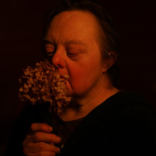 Tatyana smells a flower in her room. Tatyana was the most independent person with Down syndrome living in Svetlana. She took care of her mother and planned her funeral, and could handle life's most difficult tasks. ©Mary Gelman.