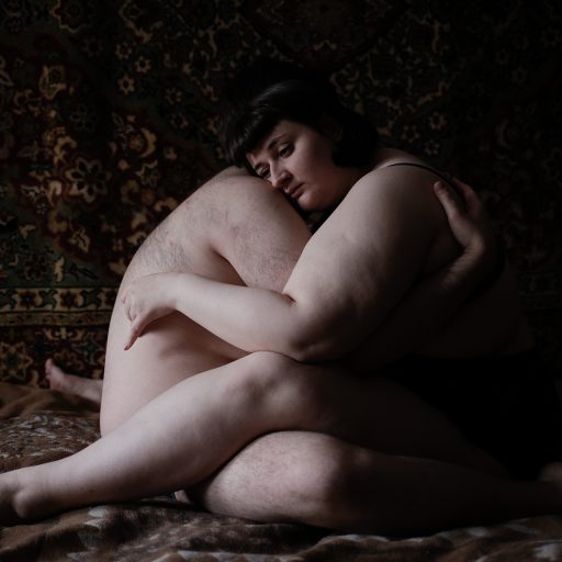 Alyona and Sasha, a couple, are photographed hugging in their room. ©Mary Gelman.

"I heard 'Pig, sow, cow, oink-oink' more often than my name. All the people in kindergarten and school insisted that I quit dancing because being a fat girl in dancing sounded like a scandal! Once at school, we were rehearsing a dance, and while I was dancing, about ten boys from the class surrounded me. They were grunting and laughing at me. I always loved to dance, but I gave it up because every time I tried, I was kicked and bullied.

It was even harder at home. My mother was ashamed of me, and my father beat me. He always thought I ate too much and controlled me. He would dump a plate of food on my head or smash it against the wall. I was afraid to eat and could starve for weeks. My mother hid food from me or cooked something I didn't like on purpose. Sometimes I ate leftovers from the kindergarten that she had picked for our dog. My father didn't care about that food, so I could reach it. When my mother was in the hospital, my brother and I stayed with our father. He locked me in a room for about five days and didn't give me anything but water. Everyone was obsessed with my weight.

For most of my life, I thought about death. It's hard to live when you are not respected and bullied solely because of your weight. A couple of times, I tried to drown myself, but my mother pulled me out. A few years ago, I found love, learned about other overweight people on Instagram, started to read about body positivity and feminism. If it weren't for that, I wouldn't be here right now."