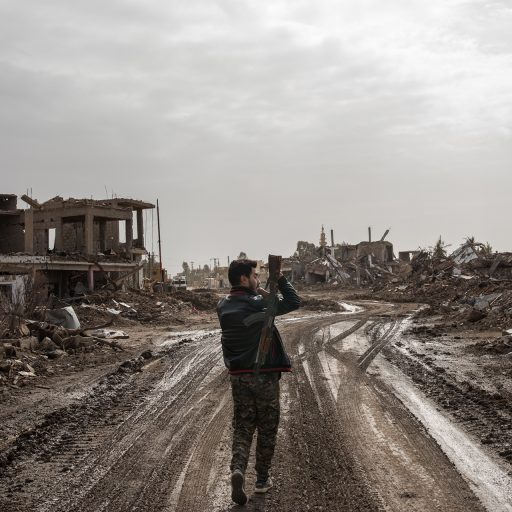 A fighter with the US backed Syrian Democratic Forces walks through the destroyed town of As Susah in Syria, on February 16, 2019. ISIS was ousted from As Susah only weeks before, as the extremist group retreated into the last sliver of territory in Baghouz along the Euphrates in south eastern Syria after a months long campaign was launched to defeat the Islamic State in Syria. While the group has lost its territory, it is already laying the groundwork for an insurgency.  

The Syrian Democratic Forces (SDF) with the support of the US-led coalition have been in a weeks-long campaign to drive out the last of the Islamic State fighters in Baghouz, who now control less than a 1.5 square mile of territory along a small portion of the Euphrates River near the Syrian border with Iraq. According to some of the civilians, ISIS blocked people from leaving the village, as fighting, the lack of food and clean water prompted dozens to leave. © Nicole Tung.