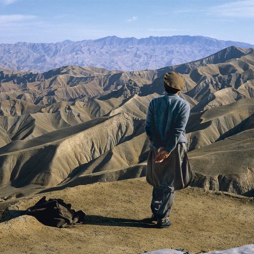 Afghanistan, 1998. Ahmad Shah Massoud above the city of Taloqan. The night before the Taliban had violated the ceasefire and attempted to take the city. Massoud is pacing back and forth on the roof of a house; he has given orders and is waiting for news of the troops in combat. © Pascal Maitre.