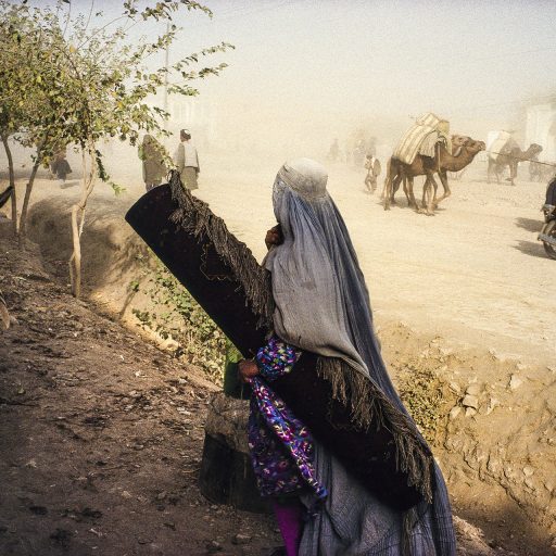 In Afghanistan, 1996, at the Andkhoy market, a widow is selling the only thing she has left: a carpet. © Pascal Maitre.