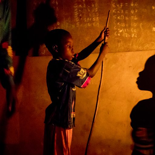 Benin, Adido. Joseph Honnon rehearses with his children, Rogatien and Eveline, what they have learned at school under the light of a paraffin lamp that emits toxic fumes. © Pascal Maitre.