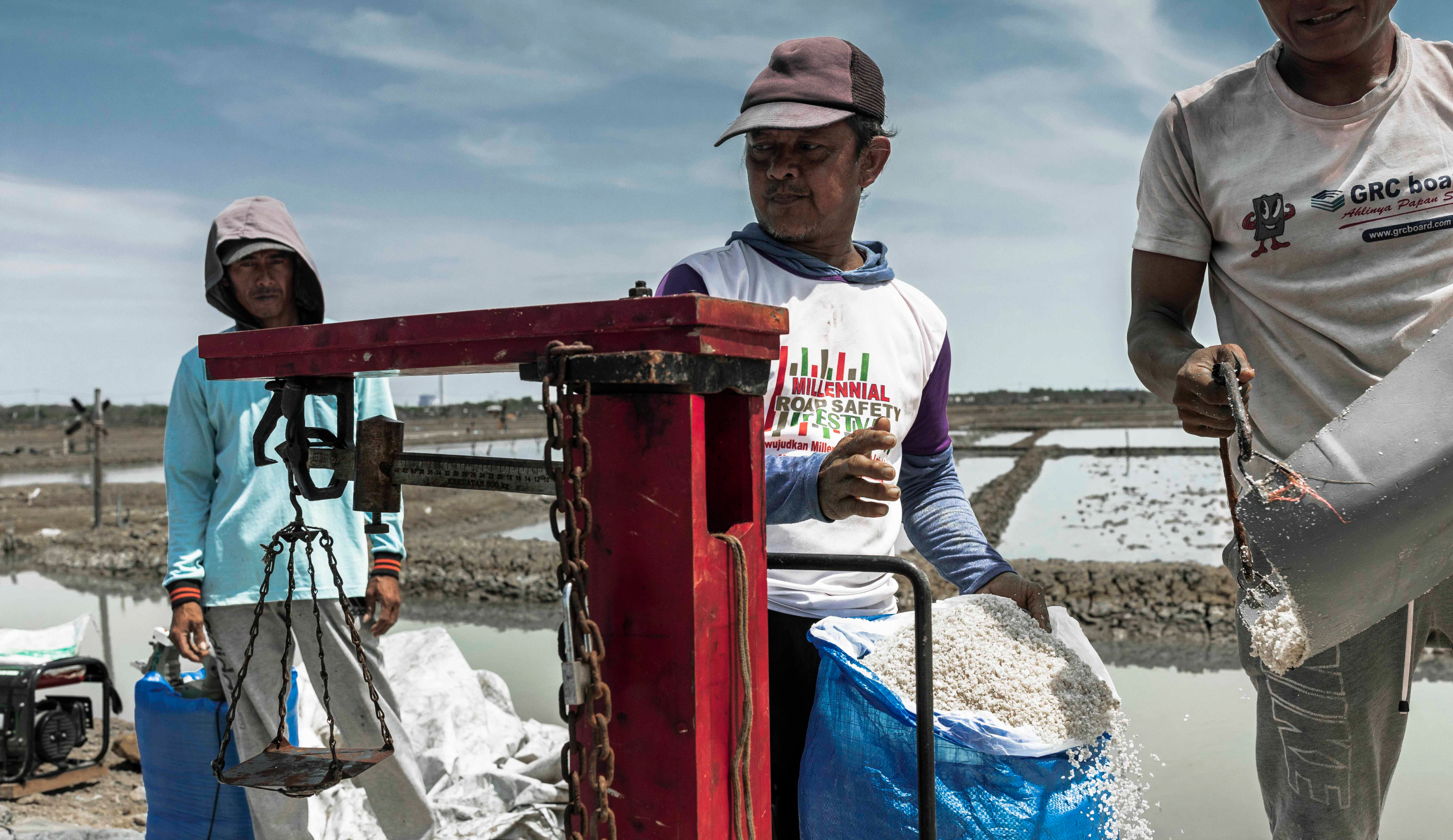 A group of men weighing and bagging a salt harvest in the village of Rawaurip, Cirebon. Salt production has fallen alarmingly in the last three years due to seawater flooding and unpredictable weather. ©Irene Barlian for VII Academy Fellows