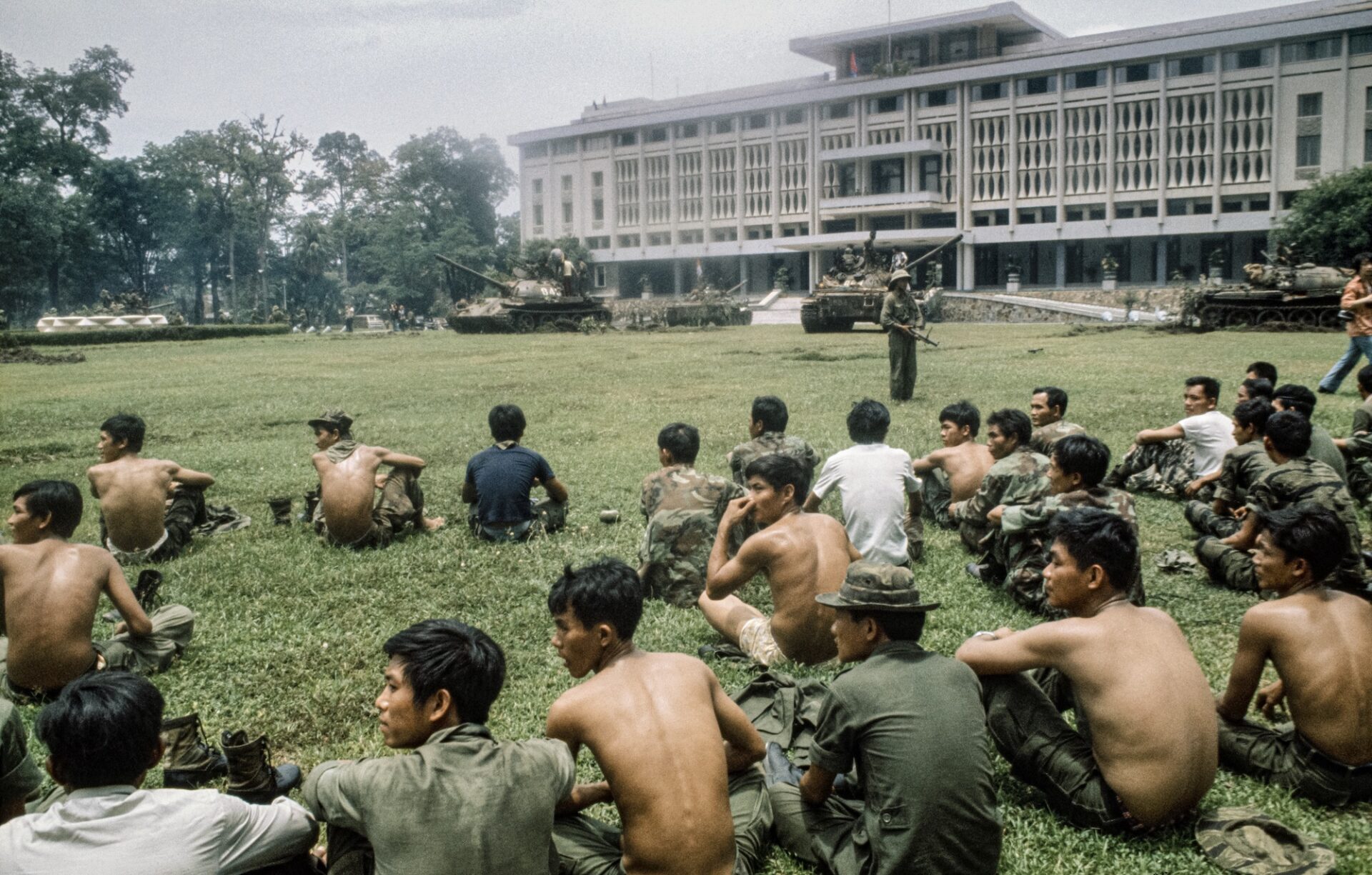 Captured South Vietnamese soldiers sit on the lawn after North Vietnamese troops seized the presidential palace in Saigon, South Vietnam, on April 30, 1975. Photo by Jacques Pavlovsky/Sygma via Getty Images.