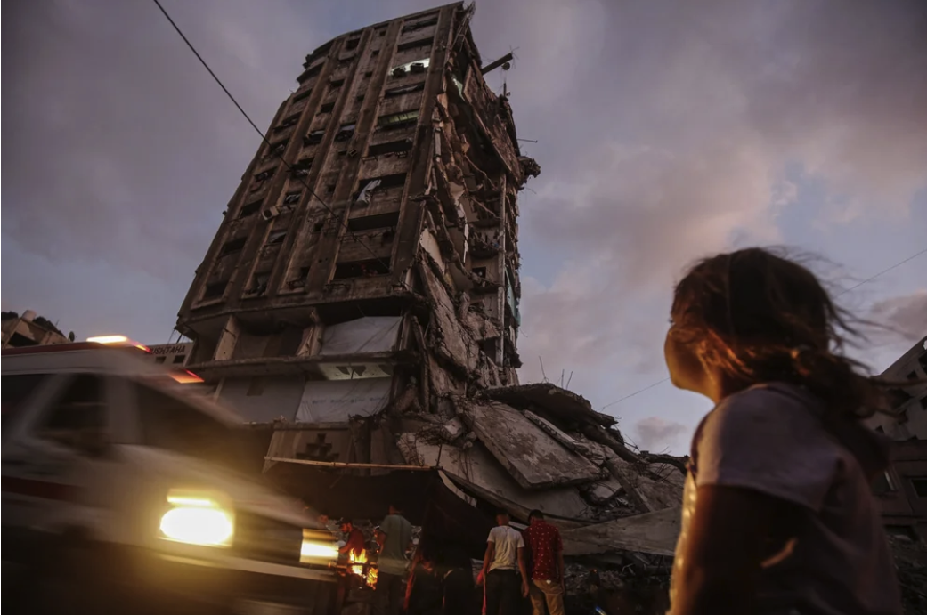 A displaced Palestinian girl looks at a partially destroyed tower block housing displaced families in Gaza City, northern Gaza Strip, on June 14, 2025.  © Omar Ashtwy.