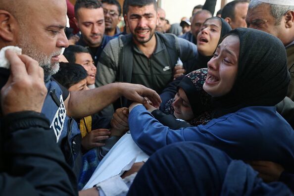 The widow (R) of Hamza Wael Dahdouh, a journalist with the Al Jazeera television network, and his father Al Jazeera’s bureau chief in Gaza, Wael Al-Dahdouh (L) mourn over his body during his funeral, after he was killed in a reported Israeli air strike, in Rafah in the Gaza Strip on January 7, 2024. Dahdouh, who was himself wounded in the arm, lost his wife and two other children in Israeli bombardment in the initial weeks of the war. (Photo by Mohammed ABED / AFP).