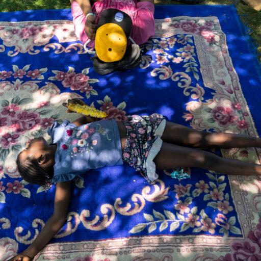 A participant in a Fourth of July barbecue hosted by the Senegalese Association of America, and the child of Senegalese immigrants, spends time near West 110th Street in Central Park in Manhattan on Friday, July 4, 2025. Members of the Senegalese community gather to celebrate the founding of the United States and spend the holiday together. © Arisa Haboshi.